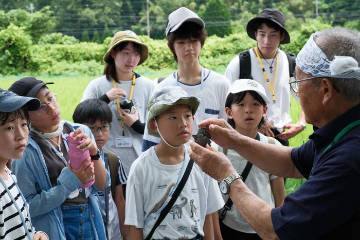 Children engrossed in listening to a story about the discovery of Tambatitanis amikitiae dinosaur fossil