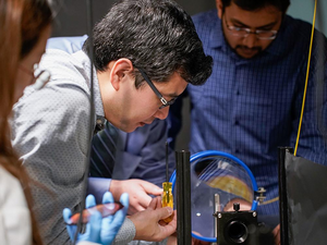 Penn State associate professor of electrical engineering, manipulates a conventional telescope lens