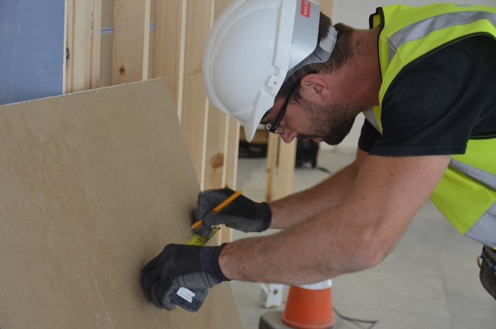 Builder measuring plasterboard