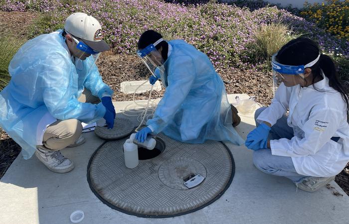 Student researchers take wastewater sample from UC Merced sewage system.