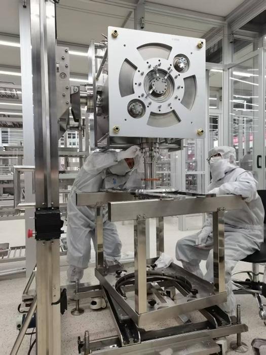 The scientific researchers are precisely docking the superconducting cavity with the coupler in the clean room.