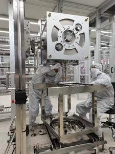 The scientific researchers are precisely docking the superconducting cavity with the coupler in the clean room.