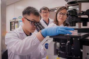 Asst Prof Eliza Fong (right) with co-corresponding author Dr. Johnny Ong (back row) from the National Cancer Centre Singapore, and another researcher from the study at work in their lab.