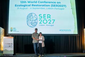 Brock Bowles, co-chair of the SER2025 conference in Denver, passing the baton to Alice Nunes, co-chair of the next edition in Lisbon.