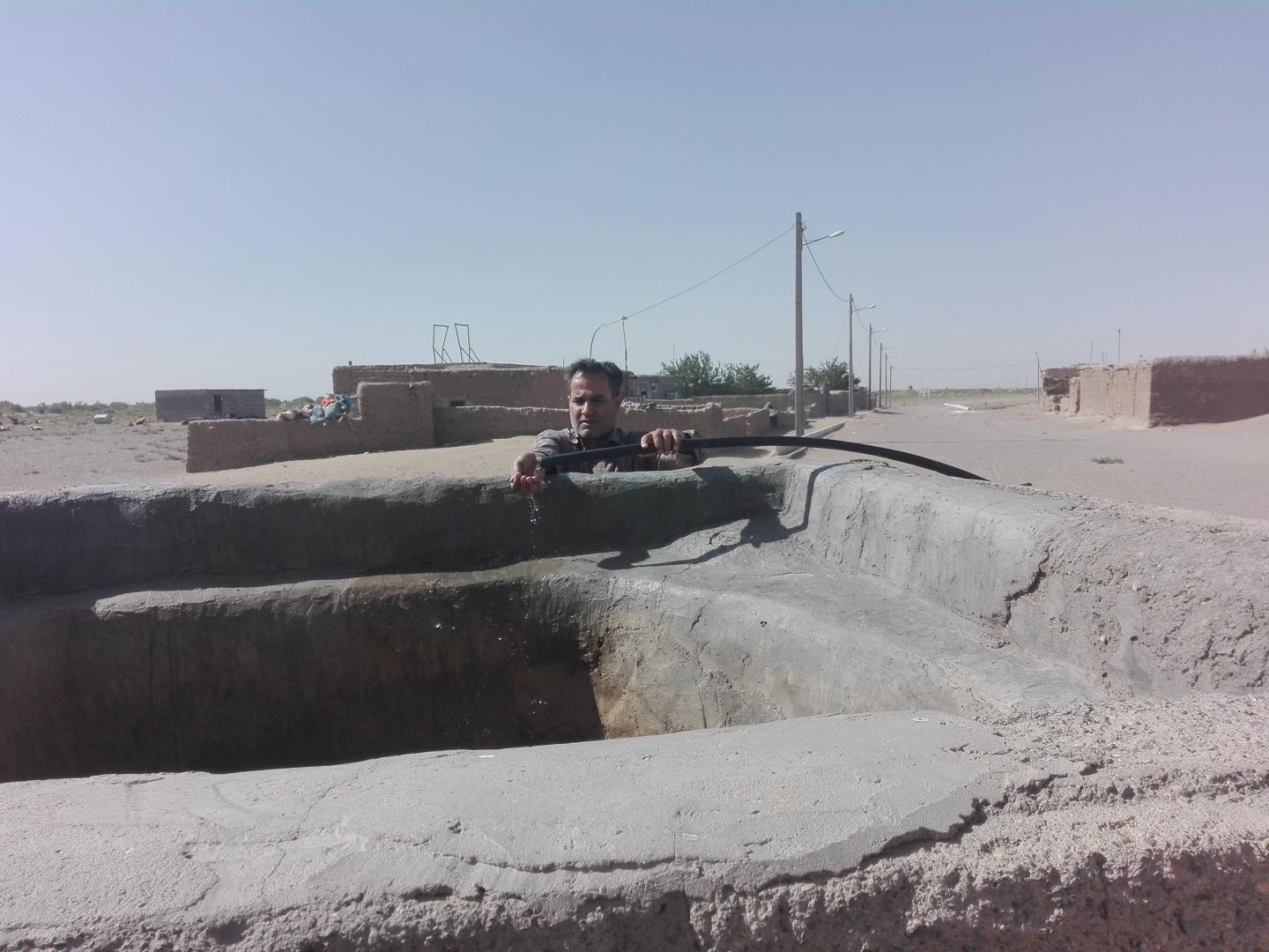 A villager examines water at a well