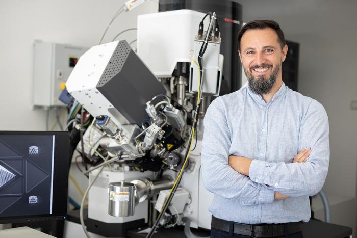 Robert Winkler next to a plasma-focused ion beam scanning electron microscope.
