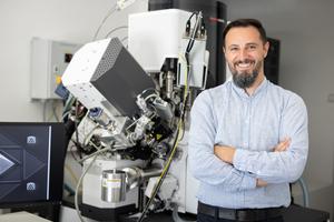 Robert Winkler next to a plasma-focused ion beam scanning electron microscope.