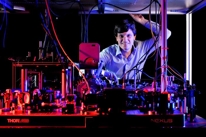 Florian Meinert and his experiment on the optical bench: The apparatus suppresses interfering blackbody radiation and enables the creation of extremely long-lived giant atoms at room temperature.