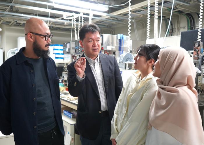 Ogino speaks about research with students and a researcher