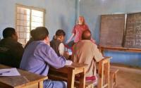 Teacher at Chalkboard in Class with Students Sitting at Desk