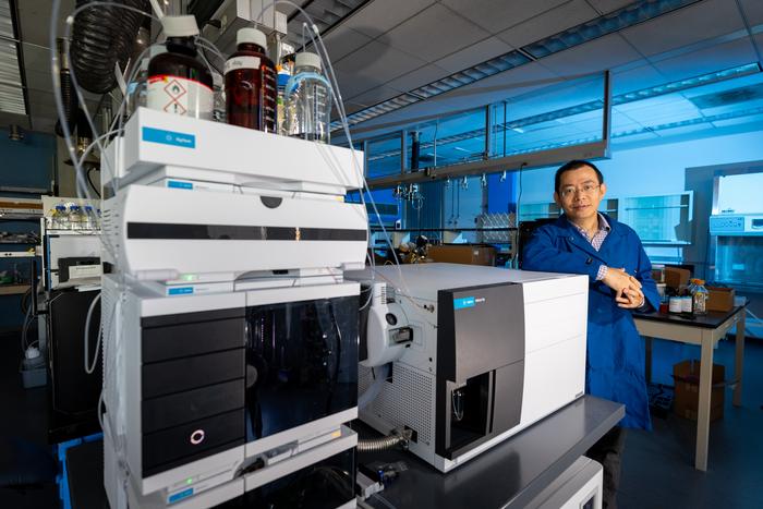 Jinyong Liu with a mass spectrometer he uses as part of his PFAS research (Stan Lim/UCR)
