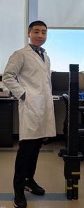 Dr. Xuyu Qian in his current laboratory, standing beside a collection of external hard drives containing raw spatial transcriptomics data from his groundbreaking human brain development research.