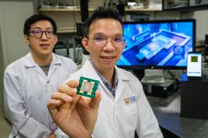 NTU Assoc Prof Y.C. Chen (right) holding the new biochip, which can detect miRNA in 20 minutes using AI, with his PhD student Fu Bowen behind him (left).