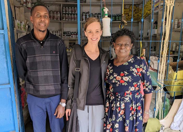 A man and two women are standing in front of a small shop with agricultural supplies