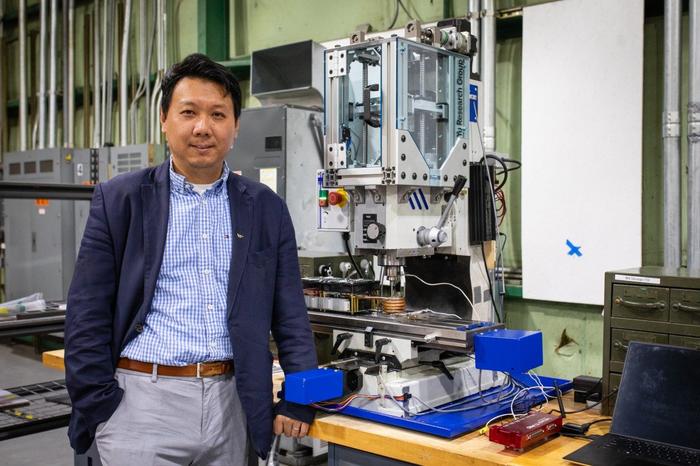 Hang Yu, associate professor of materials science and engineering, with a miniaturized additive friction stir deposition machine used in his advanced manufacturing research.