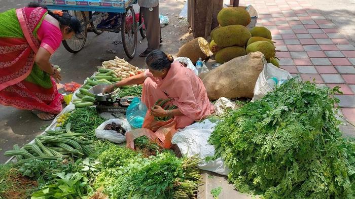 A woman selling freshly foraged greens on a Bengaluru street, connecting urban consumers with wild local foods.