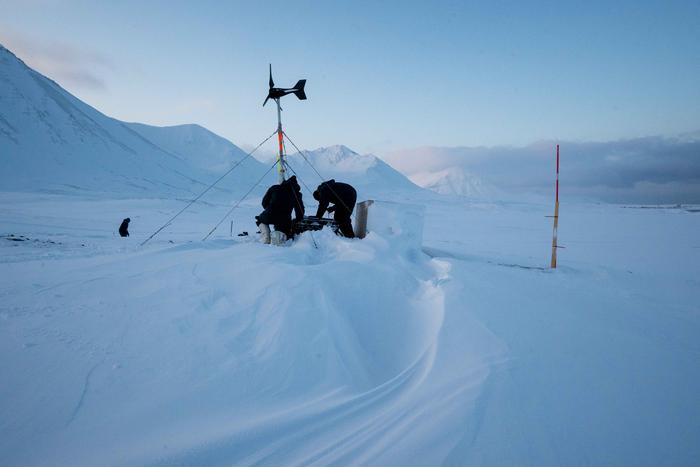 Field team working on instruments installed in the tundra soils to continuously monitor soil temperature and water content, in Svalbard, during winter.