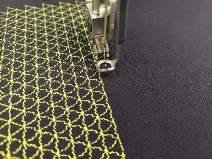 Embroidery machine stitching the triangular thread-spring pattern onto elastic fabric.