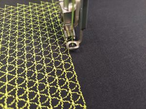 Embroidery machine stitching the triangular thread-spring pattern onto elastic fabric.