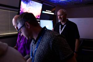 ICS 301 trainer Eric Mickelsen oversees two participants in one of the cyber escape rooms that are part of the program.