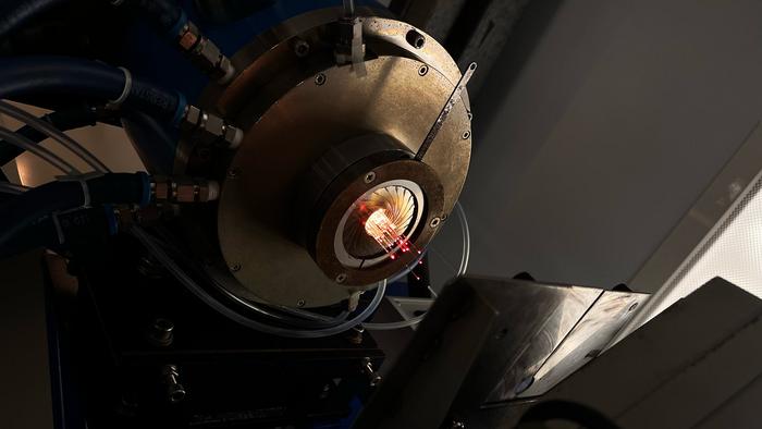 Emerging from the 2000 degree C furnace, a fibre 'stack' guides light even while it is being pulled and elongated.