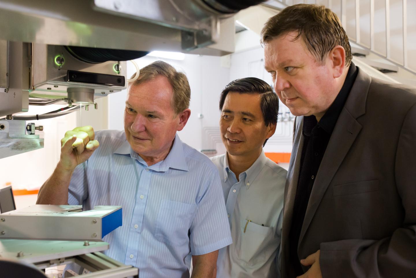 Researchers Examining a Newly Drawn Optical Fiber Cable
