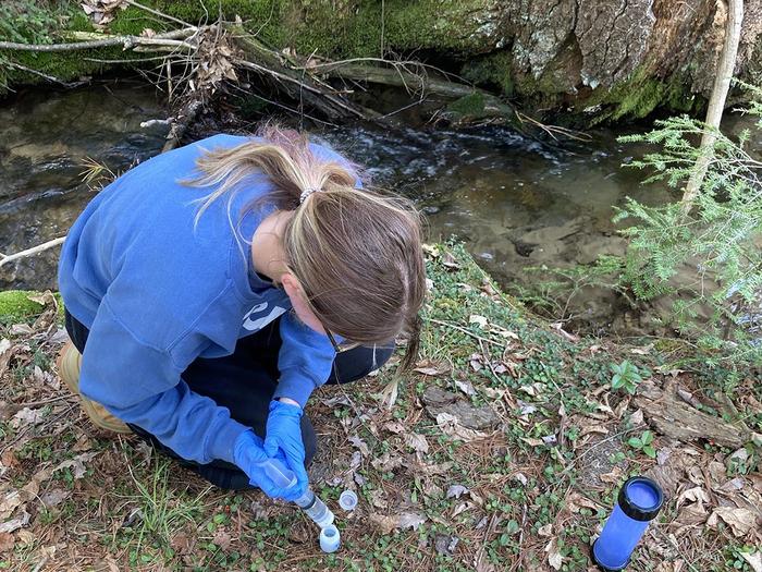 an undergraduate geosciences major takes samples at one of the well sites