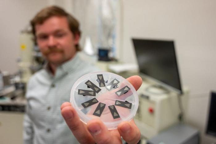 Graduate student Lukas Crockett holds up nine PFAS Detection technology devices.