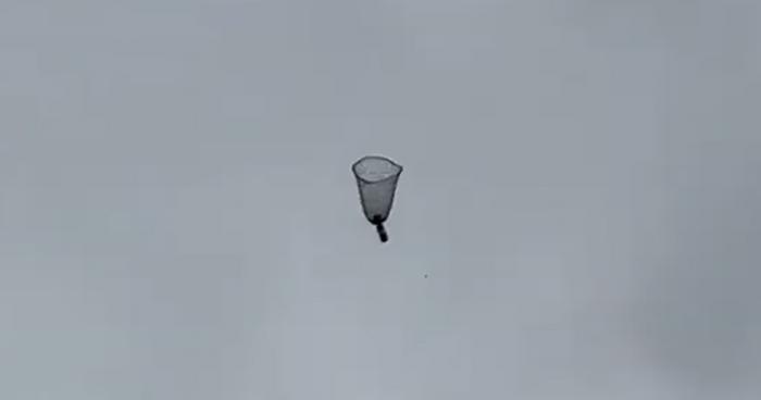 In free fall, the parachute takes the shape of an upside-down bell, slowing the descent of the weight attached to its centre.