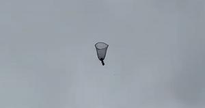 In free fall, the parachute takes the shape of an upside-down bell, slowing the descent of the weight attached to its centre.