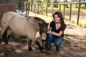 Rebecca Calisi Rodríguez kneels with mini horse