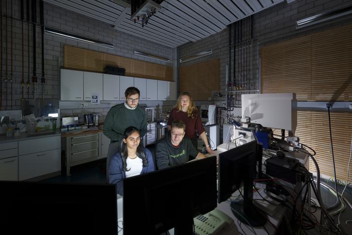 Researchers watching microscope screen