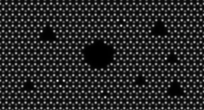 A simulated microscopy image of hexagonal boron nitride with a circular pore surrounded by triangular ones. Darker circles correspond to individual boron and brighter circles to nitrogen atoms.