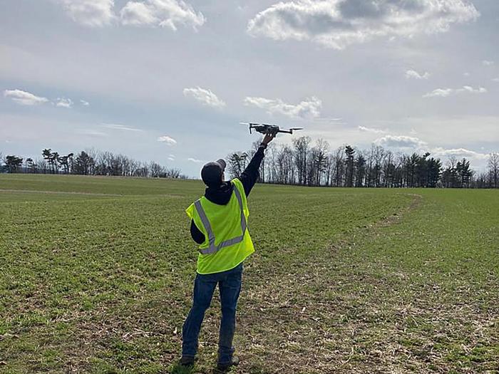 researcher launches a drone in a farm field