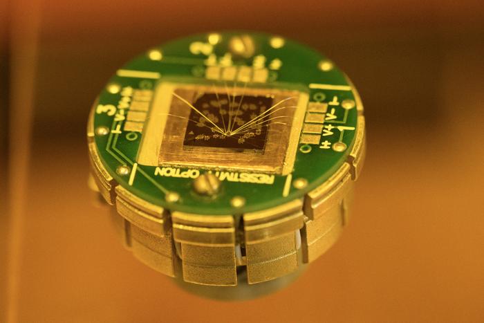 A novel, atomically thin material in tiny memory devices, here seen as clusters of golden dots on the top of the chip