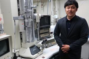 Sugimoto speaks about his research in front of the electron microscope installed at his laboratory.