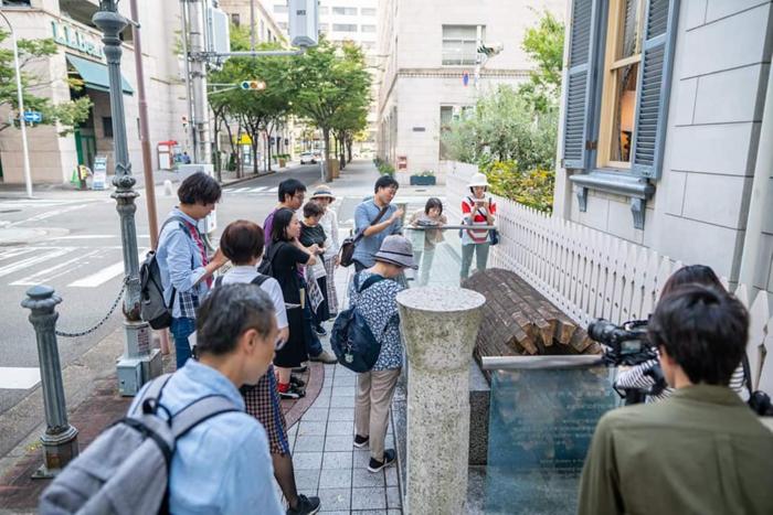Koshiro explains the brick sewer pipes of the Meiji era during a city walk event in Kobe.