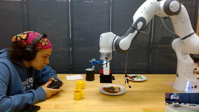 Maya Keely works with a robot as it is programmed to respond to input to create a pizza.
