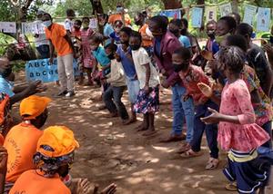 A large group of African school children engaging in activities in an outdoor setting