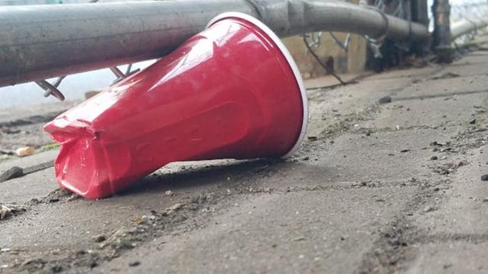 A red plastic cup discarded on a sidewalk