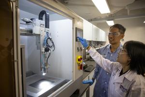 The researchers with an ultrasonic spray coating machine used to deposit the catalyst material onto the electrode.