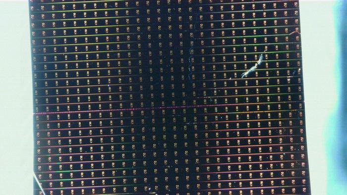 The researchers used waveguides—microscopic channels fabricated on a silicon wafer—to guide light. Long waveguides of varying widths can be seen on the chip, where a thin layer of organic molecules transforms light as it passes through