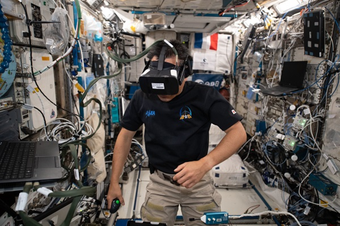 Astronaut Akihiko Hoshide is pictured wearing a virtual reality headset and clicking a trackball for Time Perception