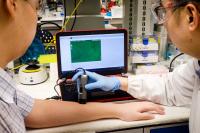 Dr. David Yeo Using a Microscope to Detect the Nanoflares Which Are Applied to the Skin Of Dr. Chris