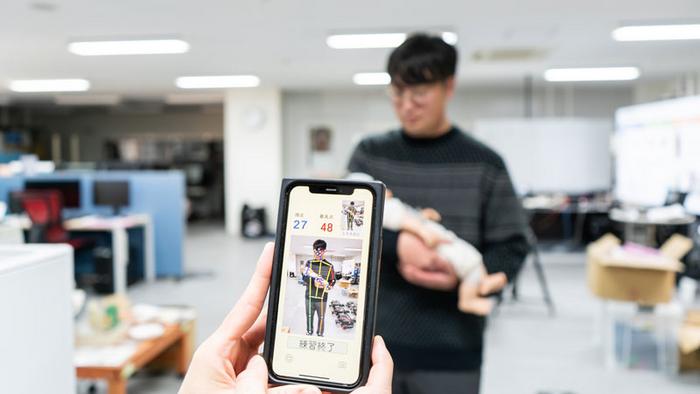 Assistant Professor Miyauchi demonstrates how the baby-holding posture guide app works