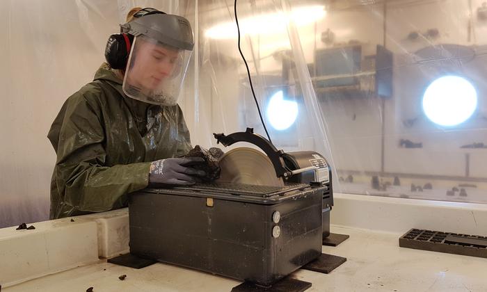 A scientist aboard the METEOR cuts through a volcanic rock sample recovered from King's Trough from a depth of several thousand meters (photo: Fabian Hampel)