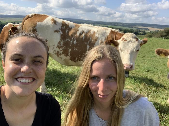 Dr Natascha Grinnell and Dr Dina Hamidi in front of a cow wearing a "Nofence" collar.