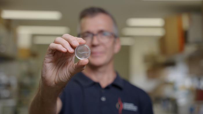 Griffith University's Professor James St John holding a nerve bridge