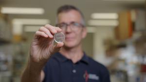 Griffith University's Professor James St John holding a nerve bridge