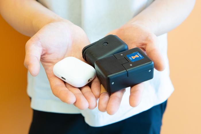 Han Keun Lee displays an AirPods case (left) along with the similarly-sized VPod (rear) and VPodDuo (right) testing devices.